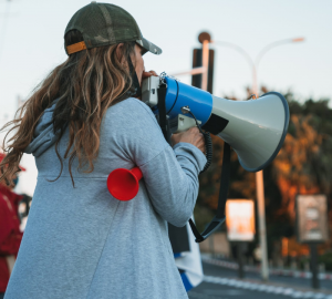 A woman protestor making a public statement with a speaker 